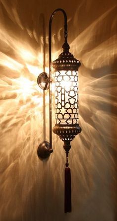 a wall light that is hanging on the side of a wall with an intricate design