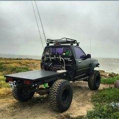 an off road vehicle parked on the side of a dirt road next to the ocean