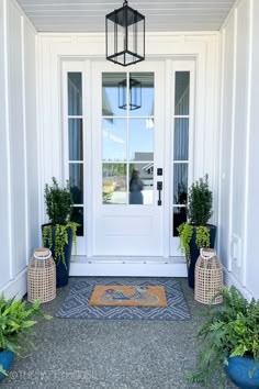 a front door with two planters and a rug on the ground in front of it