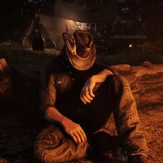 a man sitting on the ground in front of a tent at night with his hand under his face