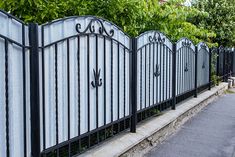 a black and white iron fence next to a sidewalk