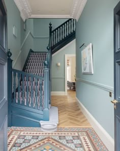 an entry way with blue walls and wooden flooring in the hallway leading to another room