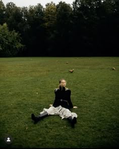 a woman sitting on the ground in a field