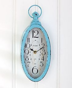 a blue clock hanging on the side of a white door with numbers painted on it