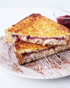 two grilled sandwiches sitting on top of a plate next to a bowl of jam