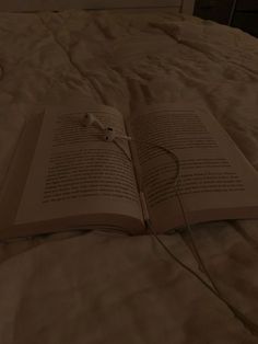 an open book on a bed with headphones plugged in to it's cover