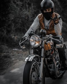 a man riding on the back of a motorcycle wearing a helmet and holding his hand up