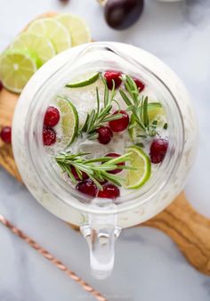 a pitcher filled with ice and cranberries on top of a cutting board