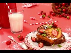 a plate with french toast and strawberries next to a glass of milk on a table