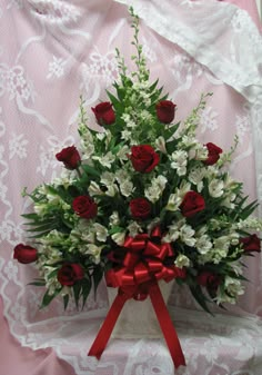 a bouquet of white and red flowers in a vase on a lace covered tablecloth