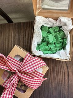 an open box with green sugar cubes in it next to a red and white checkered ribbon