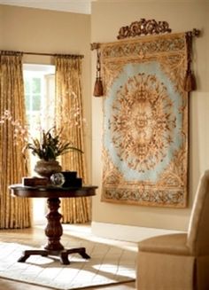 an ornate tapestry hangs on the wall above a small table in front of a window