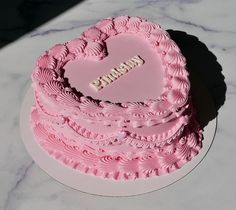 a pink heart shaped cake sitting on top of a table