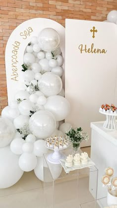 a table topped with white balloons and cupcakes