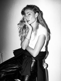 a black and white photo of a woman sitting on a chair with her hand under her chin