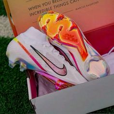 a pair of nike soccer cleats are in a box on the grass,