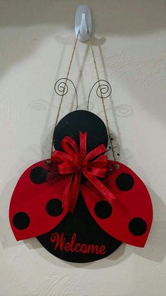 a welcome sign with a ladybug hanging from it's side on a wall