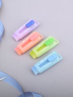 four different colored toothbrushes sitting next to each other on a white surface with a blue ribbon