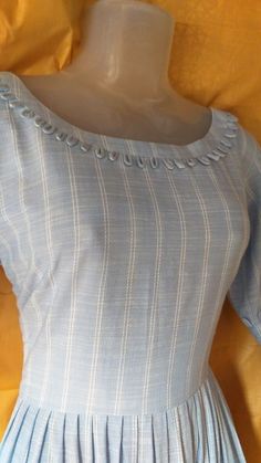 a mannequin wearing a blue dress with white stripes on the chest and shoulders