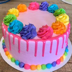 a rainbow cake with icing and colorful flowers on the top is ready to be eaten