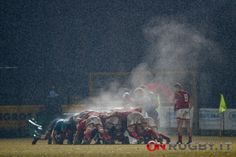 a group of men standing on top of a field next to each other in the rain