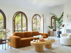 a living room filled with lots of furniture and large arched windows in the wall behind it