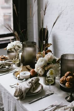 the table is set with silverware and flowers in vases on top of it