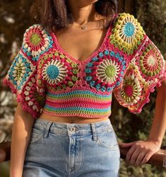 a woman wearing a colorful crochet top and jeans