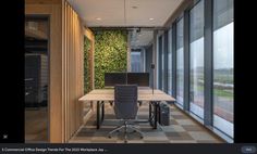 an office with two computer monitors on the desk and a green wall in the background