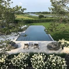 an outdoor swimming pool surrounded by lush green grass and white hydrangeas with chairs around it