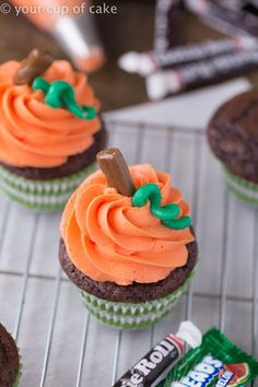 some cupcakes with orange frosting and green icing