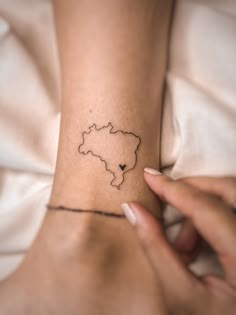 a woman's arm with a small map tattoo on her left wrist and the outline of a heart