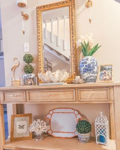 a wooden table topped with a mirror and vases