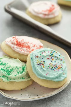 three decorated cookies on a plate with sprinkles and frosting in the middle