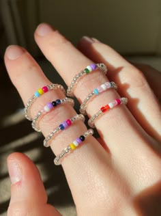 a woman's hand with five rings on it, all in different colors and sizes