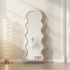 a large white mirror sitting on top of a wooden floor next to a vase and lamp