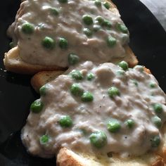 two pieces of bread topped with peas and gravy on top of each other