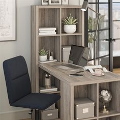 a computer desk with a laptop on top of it next to a chair and bookshelf