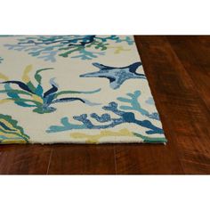 an area rug with blue and yellow corals on it, sitting on a wooden floor