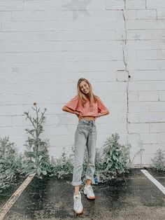 a woman standing in the rain with her hands on her hips and wearing an orange shirt