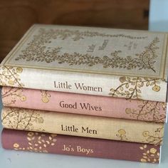 four books stacked on top of each other in front of a wooden box with the title little women good wives