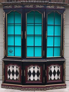 a black and white checkered china cabinet with glass doors on the front, in front of a house