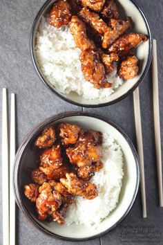 two bowls filled with chicken and rice next to chopsticks on a table top