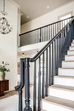 a staircase leading up to the second floor with chandelier hanging from the ceiling