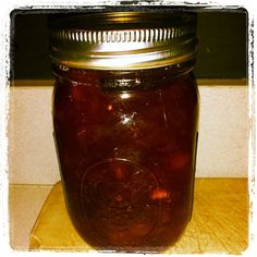 a glass jar filled with red liquid sitting on top of a table