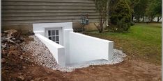 a white building with a window in the middle of it and gravel on the ground next to it