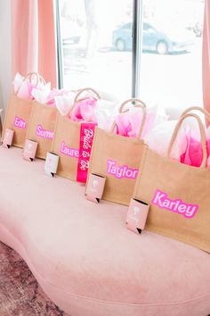 several bags with name tags on them sitting on a pink bench in front of a window