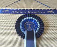 a blue ribbon is attached to a sign that says abie's rosettes