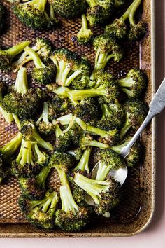 cooked broccoli florets in a baking dish with a serving utensil