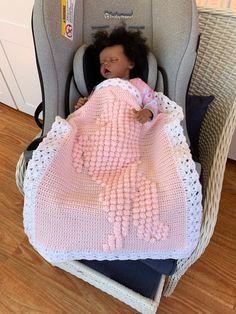 a baby sleeping in a car seat with a pink blanket on it's back